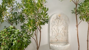 Un lavamanos empotrado en la pared con un diseño decorativo, rodeado de plantas verdes.