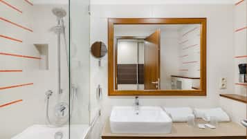 A modern bathroom with a glass-enclosed shower, a large mirror, and a wooden vanity with a sink.