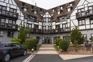 A traditional European-style building with a symmetrical facade, multiple balconies with flower boxes, and a central entrance with steps. - Hôtel Les Alizés (Lipsheim)
