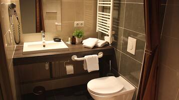 Une salle de bain moderne équipée d’un lavabo, d’un miroir, d’un porte-serviettes et de toilettes.