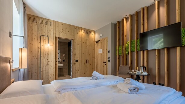 Une chambre d’hôtel avec deux lits, une télévision, un bureau avec une chaise et une salle de bain visible à travers une porte ouverte.