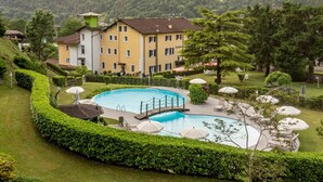 Un hôtel doté d’une piscine, entouré de haies et d’arbres bien entretenus.