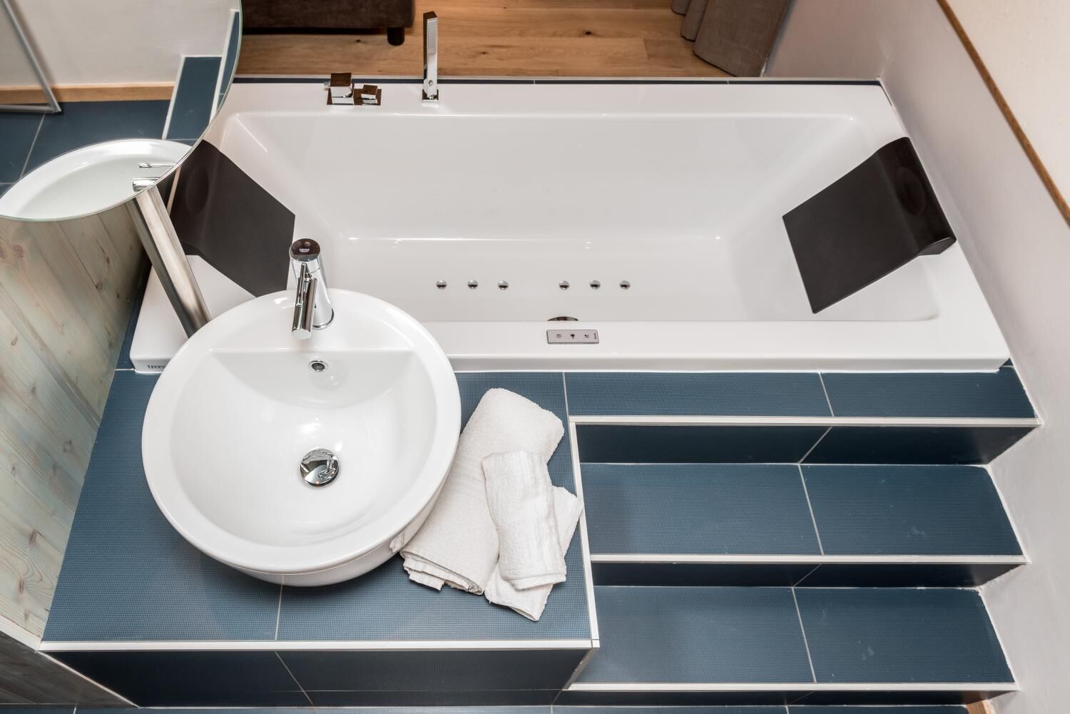 A modern bathroom with a white bathtub, a round sink, and a towel on the counter.