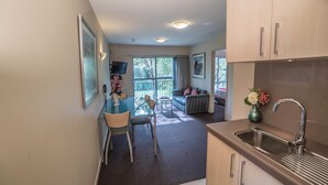 A modern kitchen with a sink, dining table, chairs, and a view of the living area. - 162 Kings of Riccarton Motel (Christchurch)