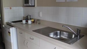 A kitchen with a stainless steel sink, a microwave, and a coffee maker on the counter.
