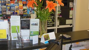 A reception desk with brochures, a vase of orange lilies, and a calendar.
