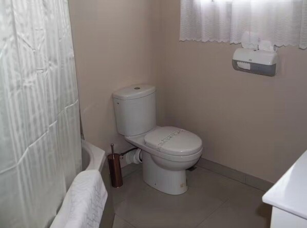 A small bathroom with a toilet, a towel rack, and a tissue dispenser. - Asure Camelot Arms Motor Lodge (Auckland)