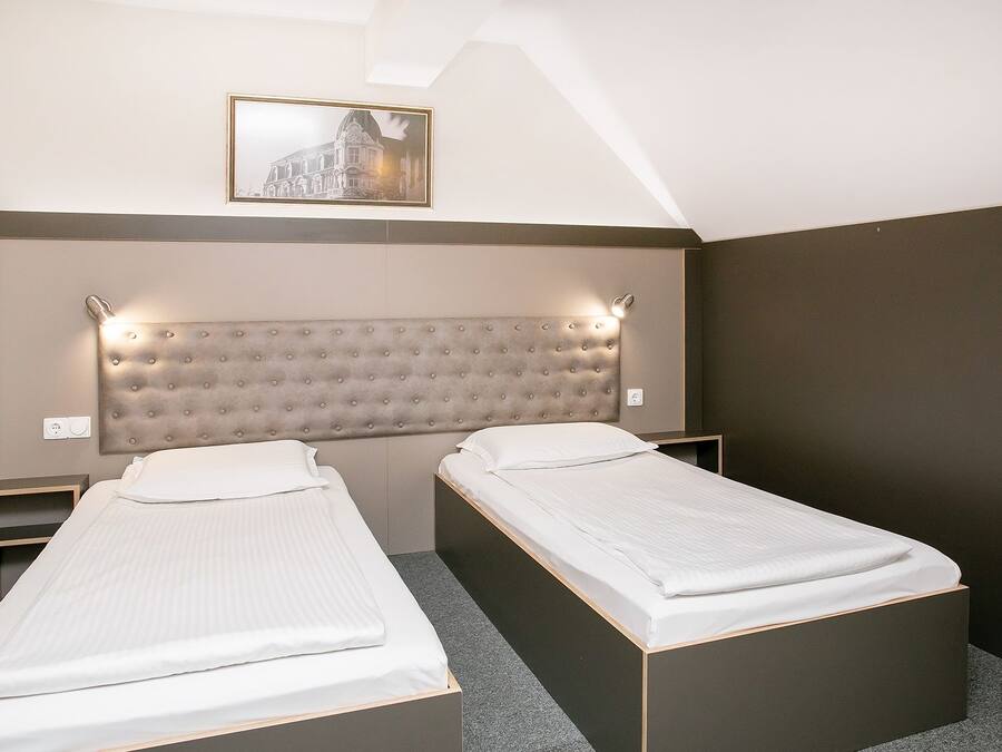 Una habitación de hotel con dos camas individuales, un amplio cabecero acolchado y un cuadro en la pared.