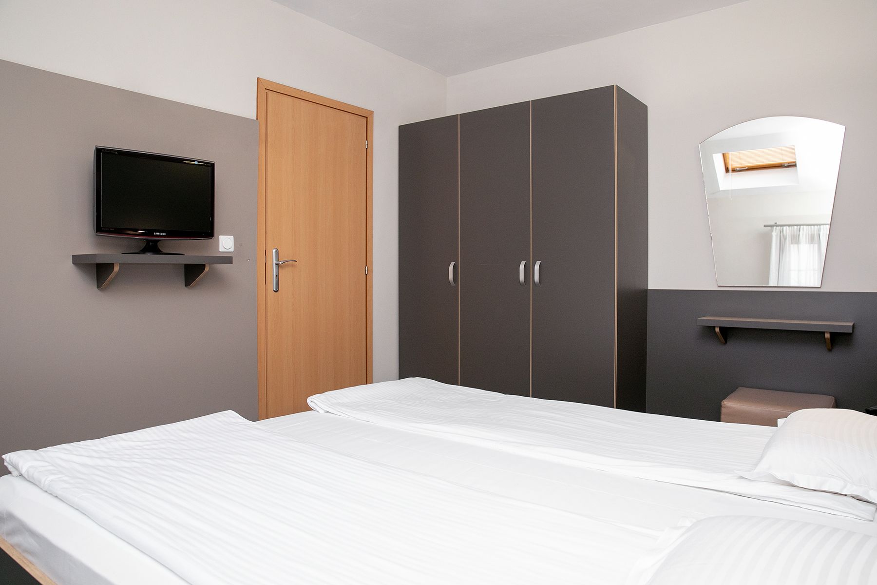 Un dormitorio con cama, armario, televisor y espejo.
