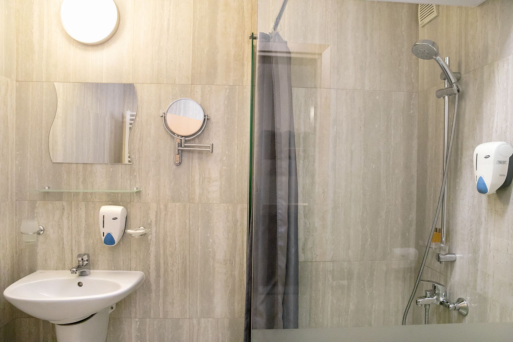 A modern bathroom with a sink, mirror, and shower.