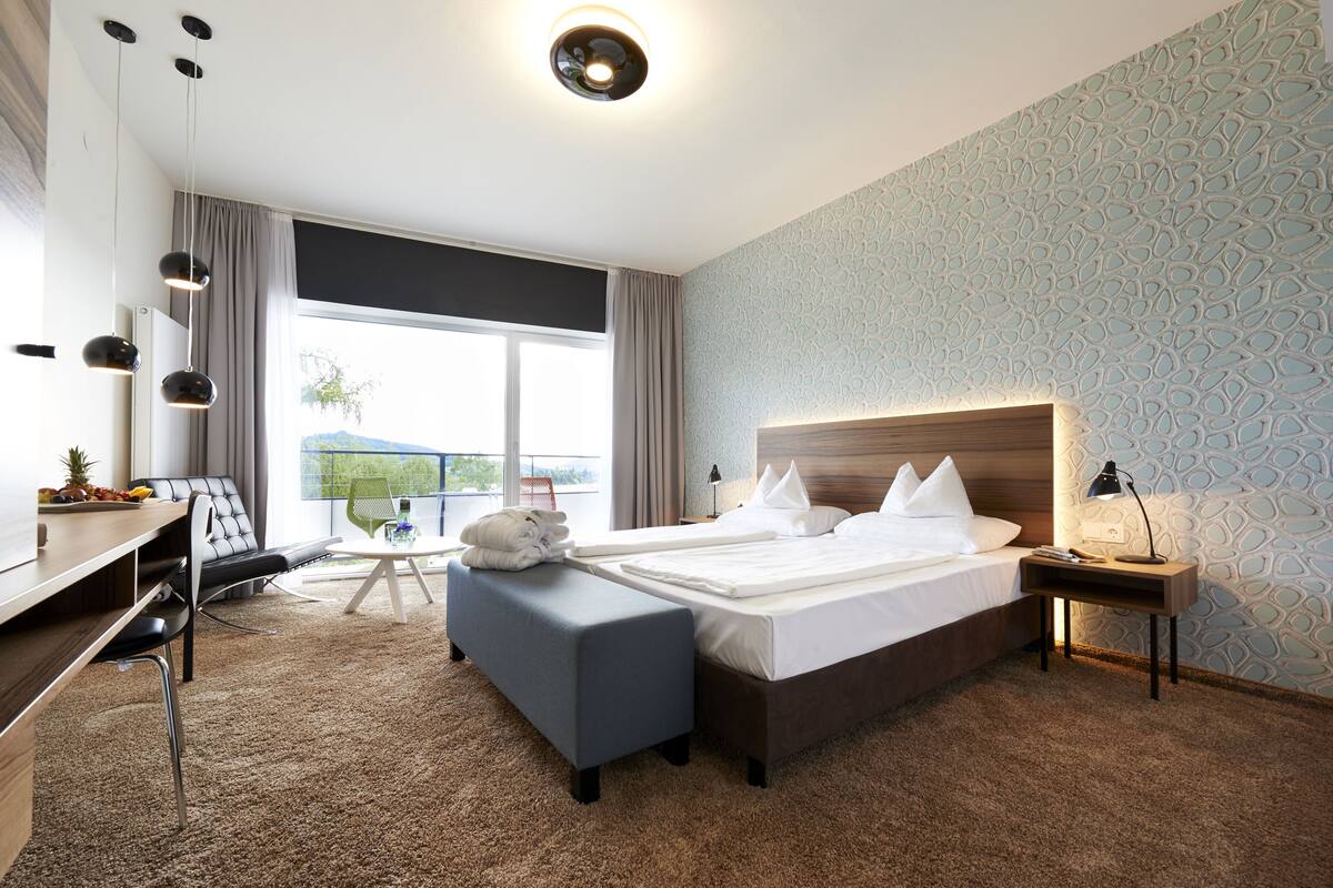 Una habitación de hotel con una cama grande, un escritorio con una silla, una mesita pequeña y un sofá.