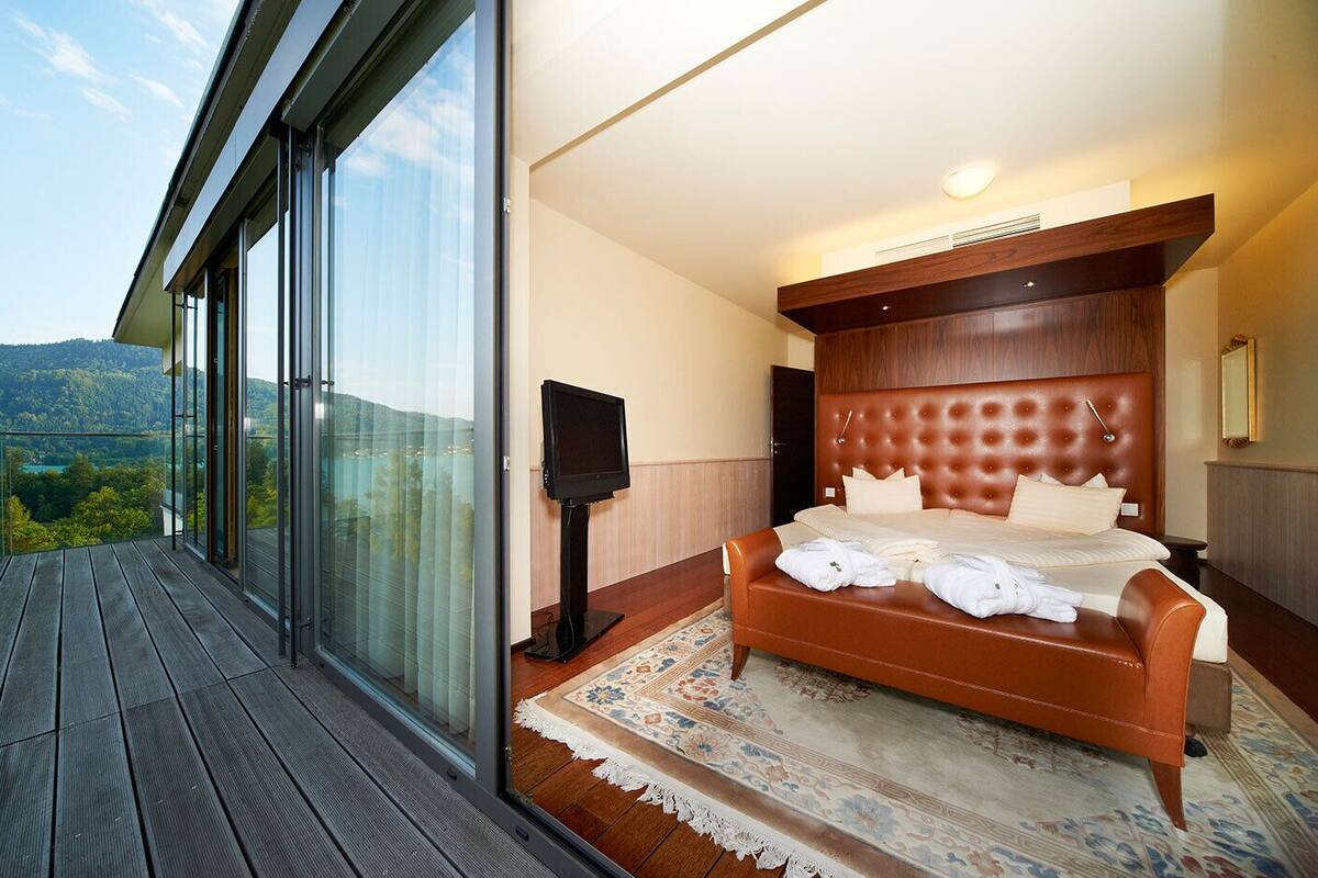 Un dormitorio moderno con una cama grande, un televisor de pantalla plana y un balcón con vistas panorámicas.