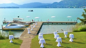 Une cérémonie de mariage organisée au bord d’un lac, avec des tables et des chaises, une jetée et des bateaux.