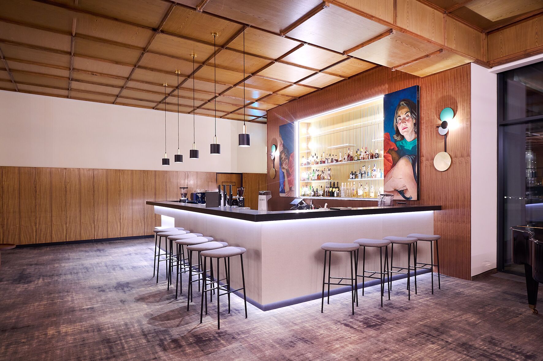 A modern bar area with a wooden ceiling, a central bar counter, and multiple stools.