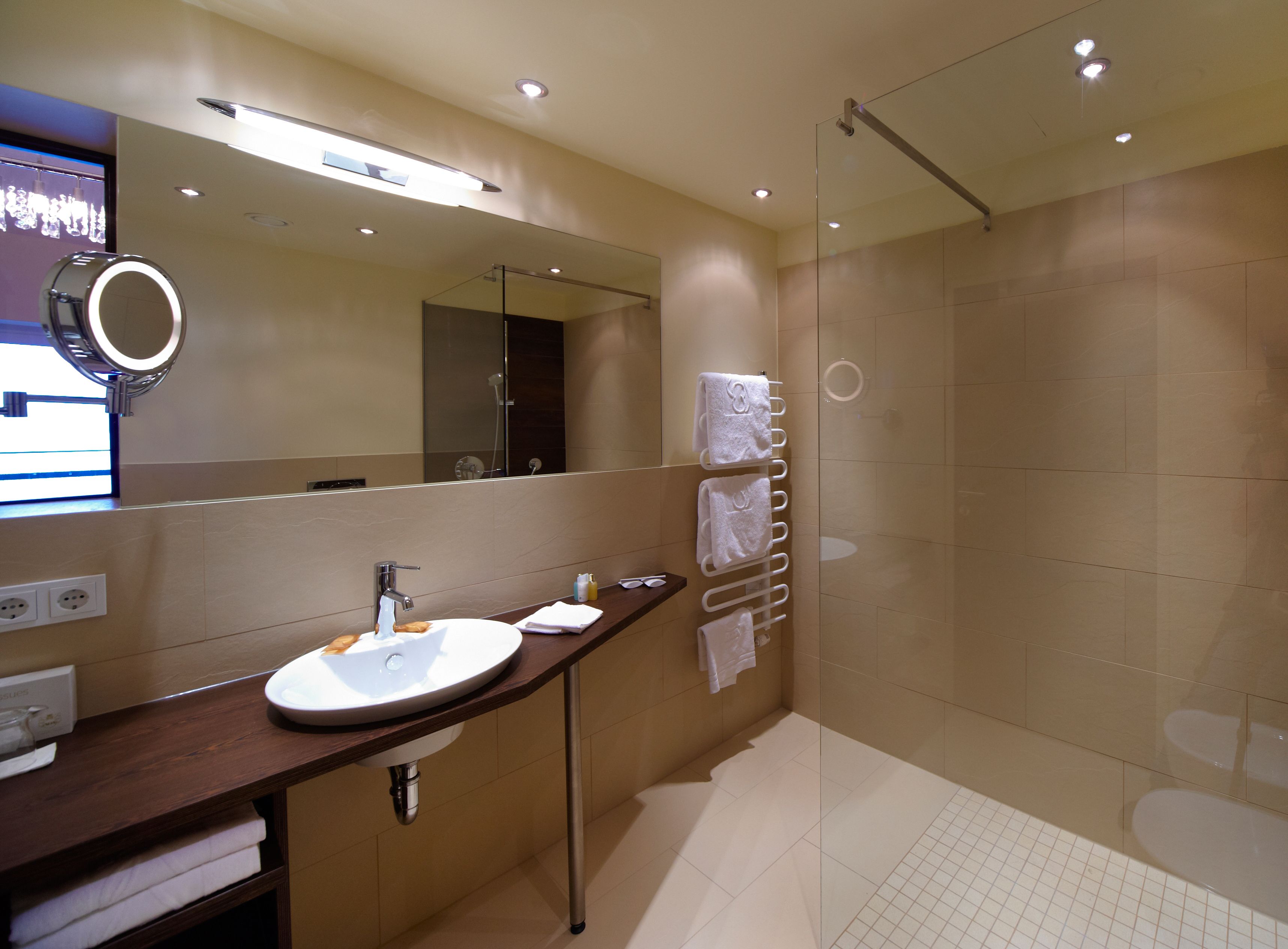 Une salle de bain moderne avec un grand miroir, un lavabo et une douche à parois de verre.