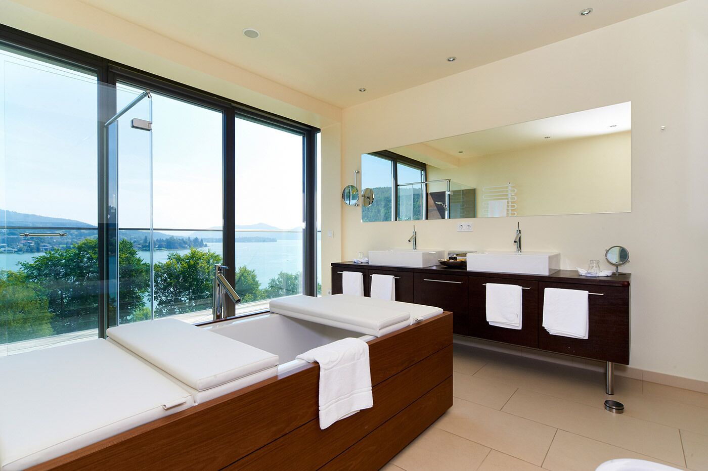 A modern bathroom with a large bathtub, dual sinks, and a large mirror.