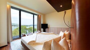 A hotel room with a large bed, a TV, and a view of a lake.