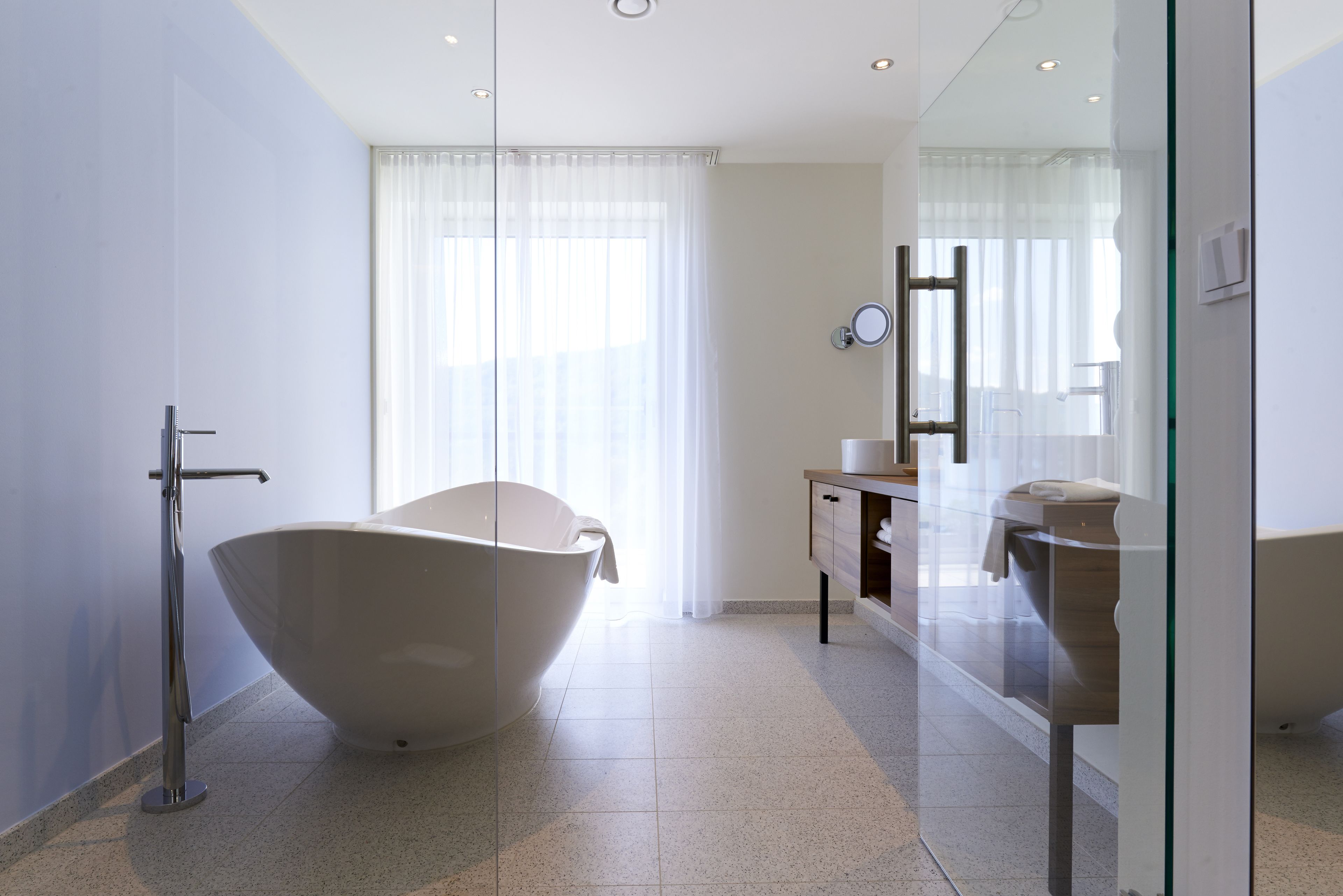 A modern bathroom with a freestanding bathtub, a glass shower enclosure, and a vanity with a mirror.