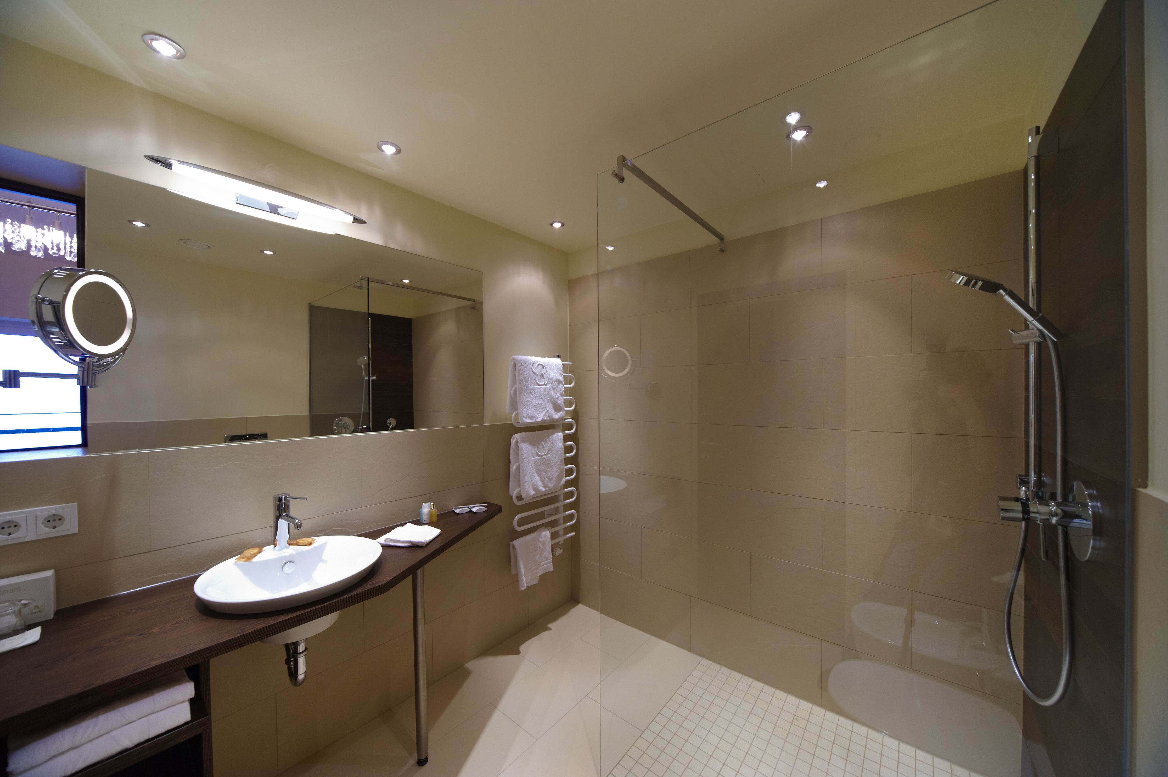 A modern bathroom with a sink, mirror, and shower.