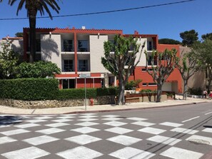 Un hotel con fachada roja y blanca, varios balcones y un paso de peatones a cuadros en su parte frontal.