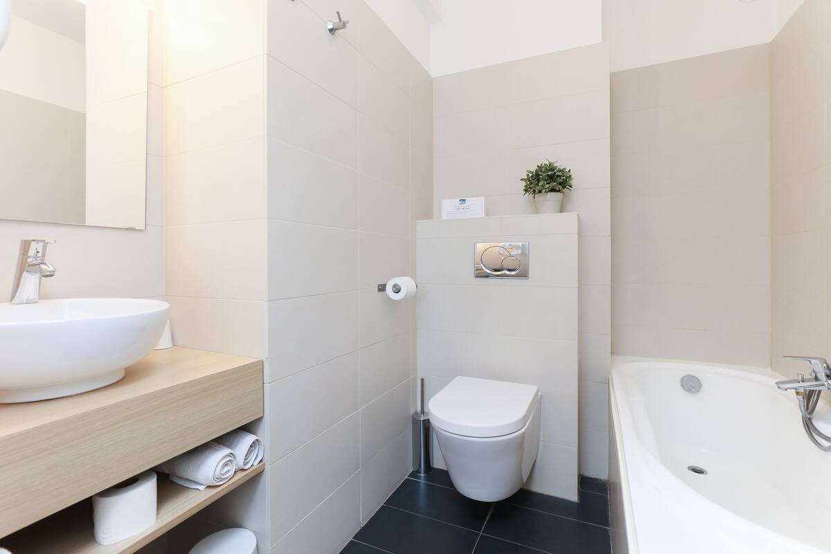 A modern bathroom with a large sink, toilet, and bathtub.