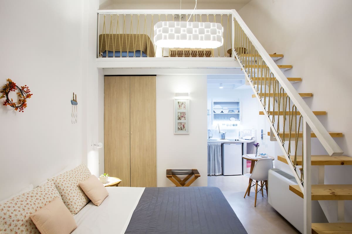 Quarto com cama, escrivaninha e escada.