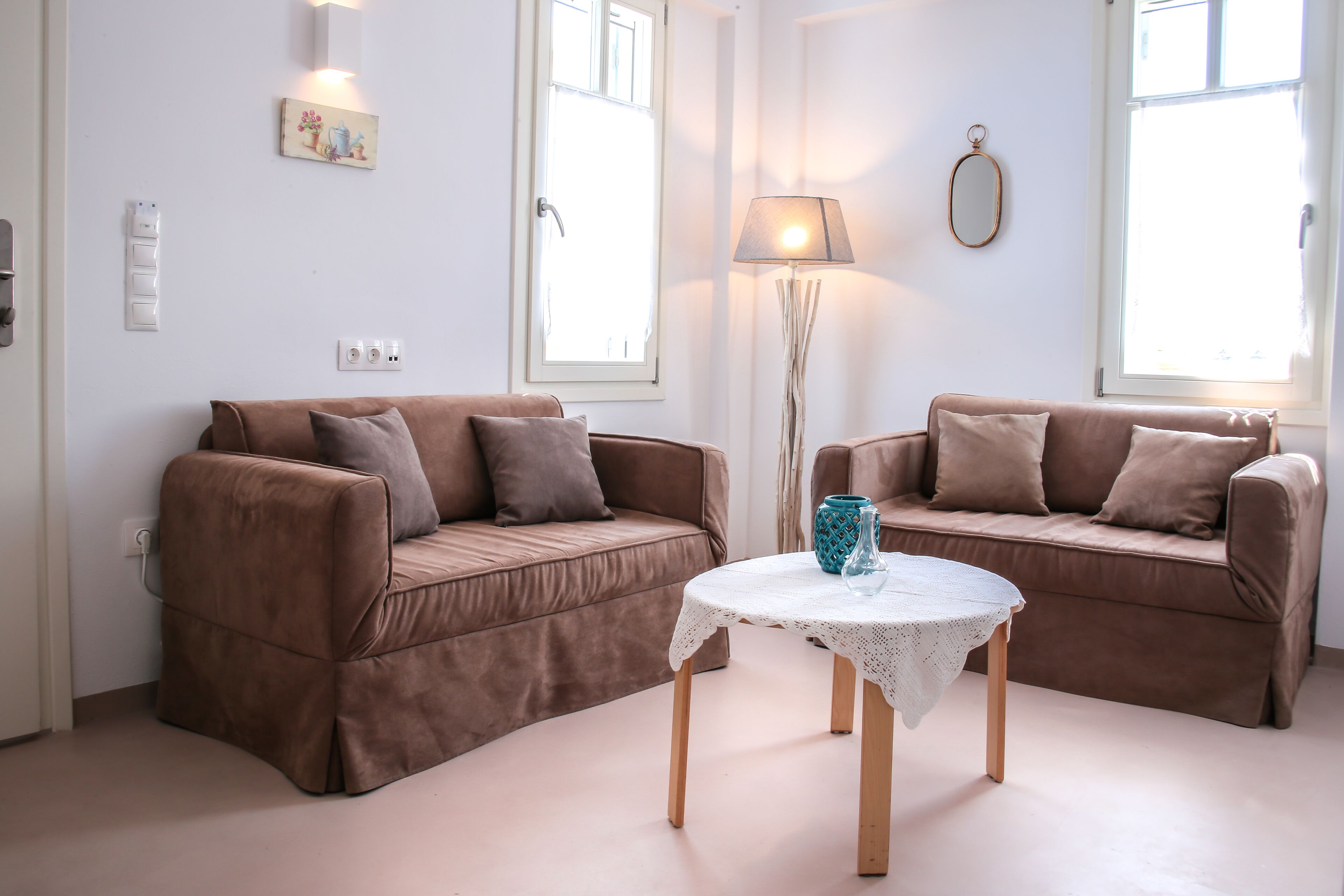 A living room with two brown sofas, a small round table, a lamp, and a painting on the wall.