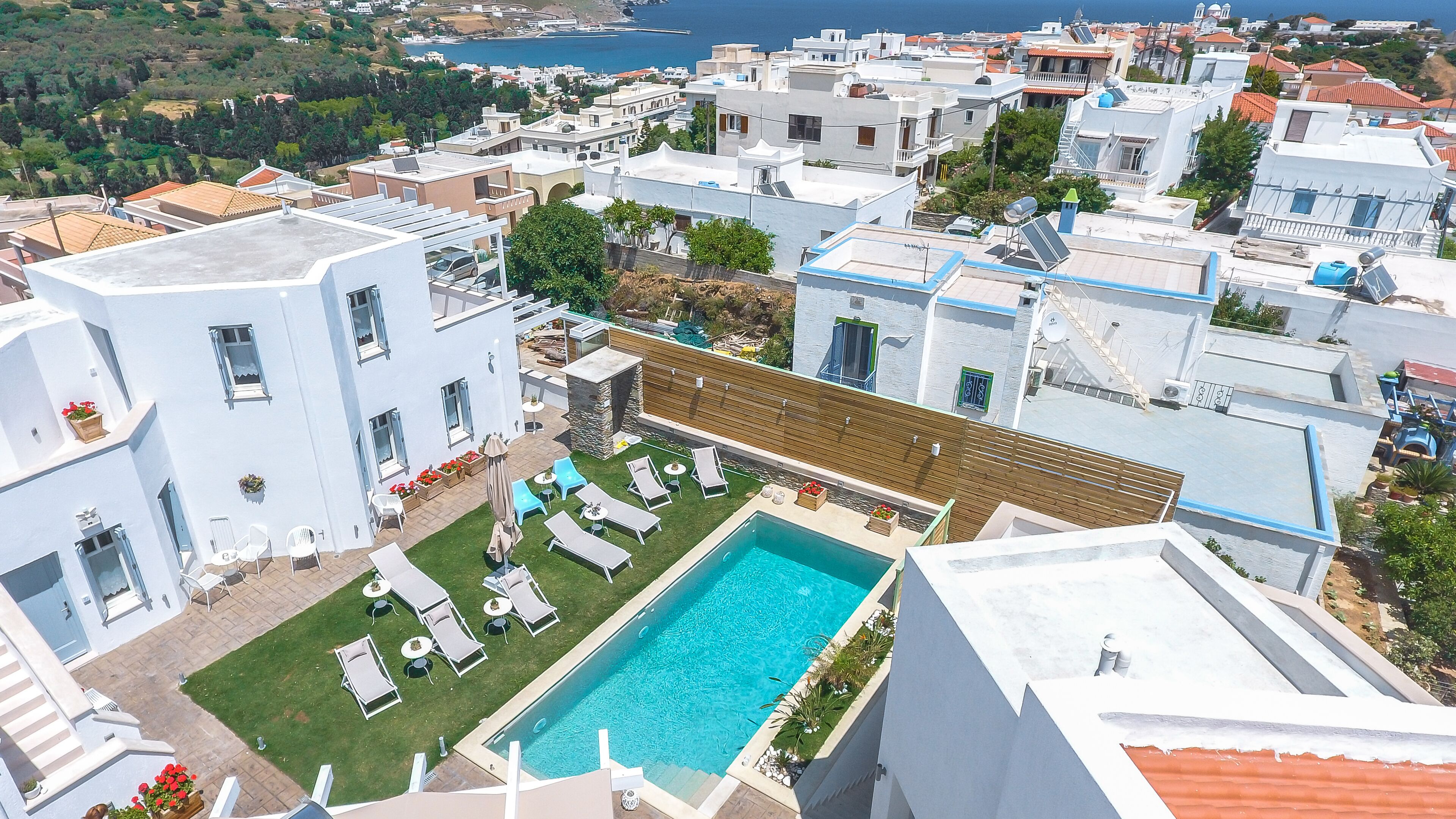 A residential area with a swimming pool surrounded by lounge chairs and a wooden deck.