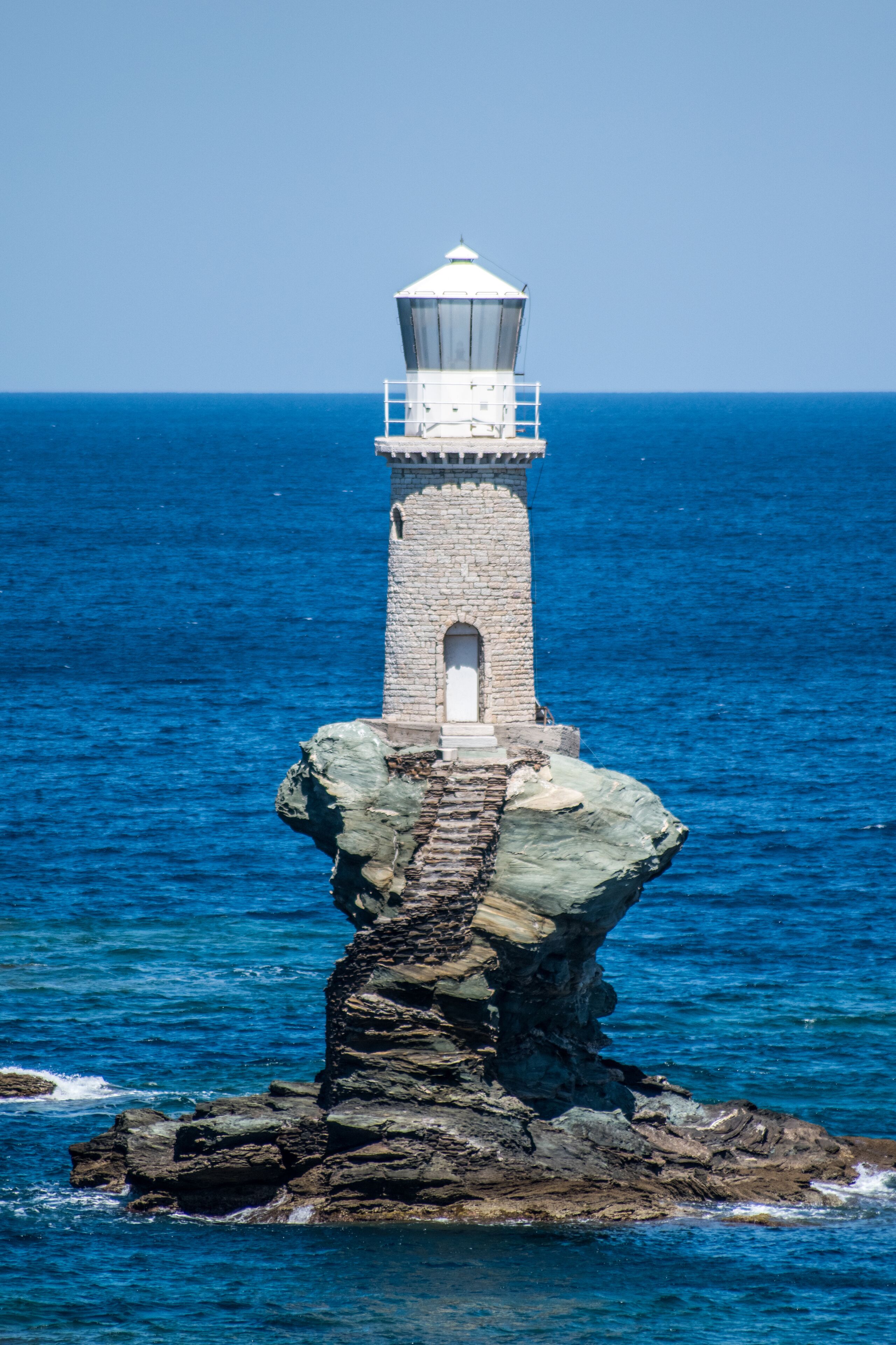 Un faro sobre un promontorio rocoso, rodeado de aguas azul turquesa.