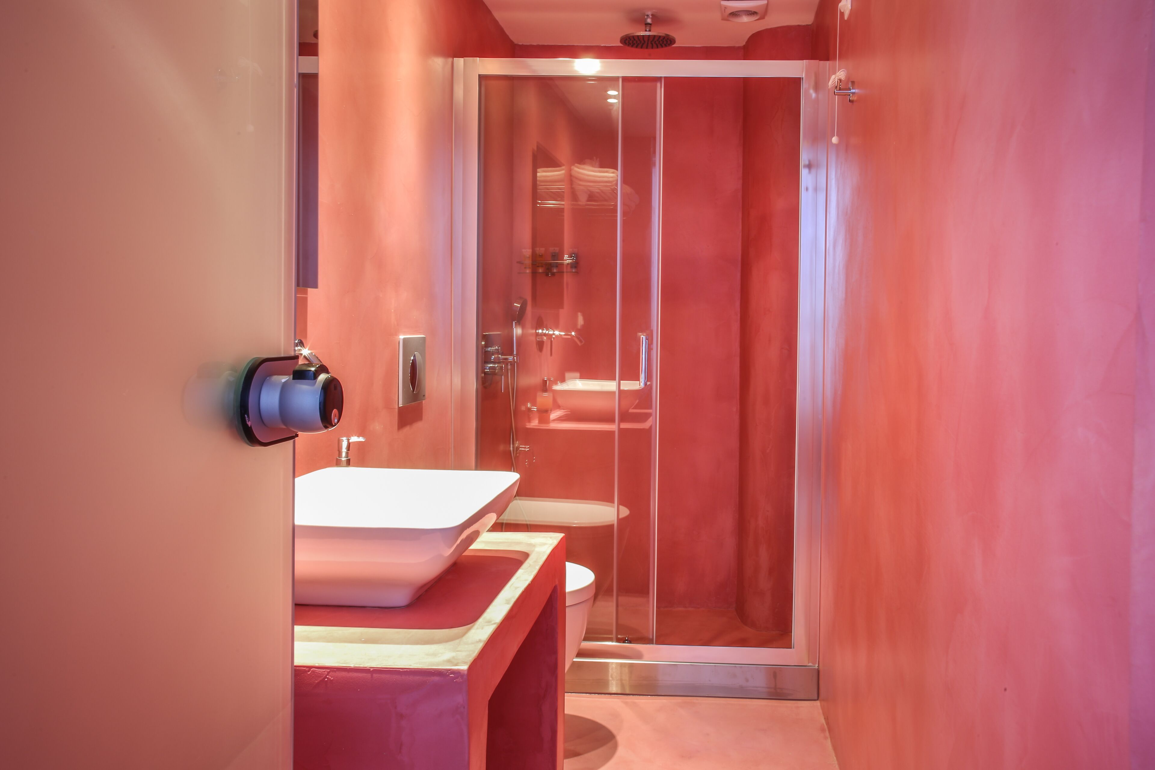 A modern bathroom with a glass-enclosed shower, a white sink, and a toilet.