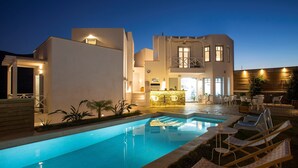 A modern house with a swimming pool, outdoor seating, and a bar area.