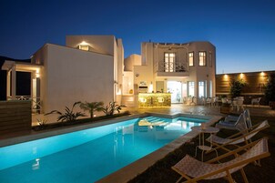 Una piscina al aire libre, sombrillas, sillones reclinables de piscina