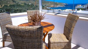 A wicker dining set with a view of the sea and hills.