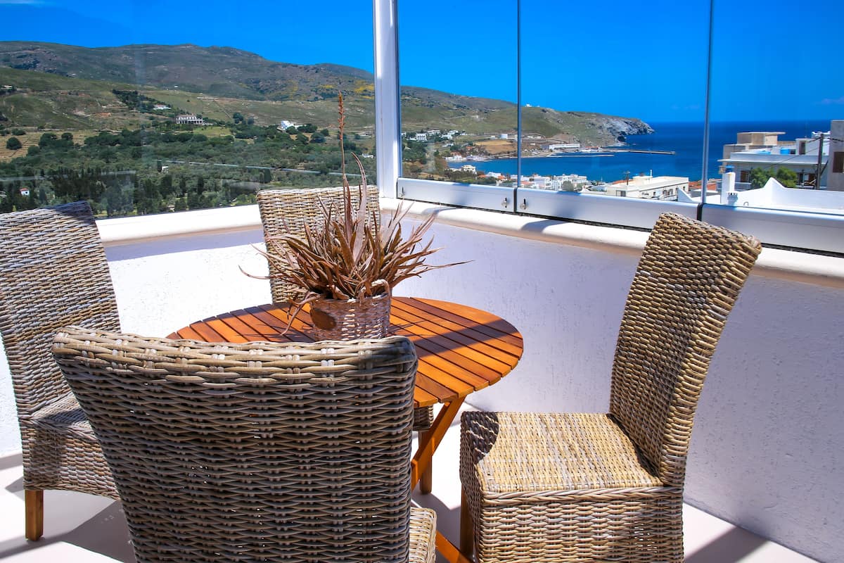 Conjunto de jantar em vime com vista para o mar e colinas.