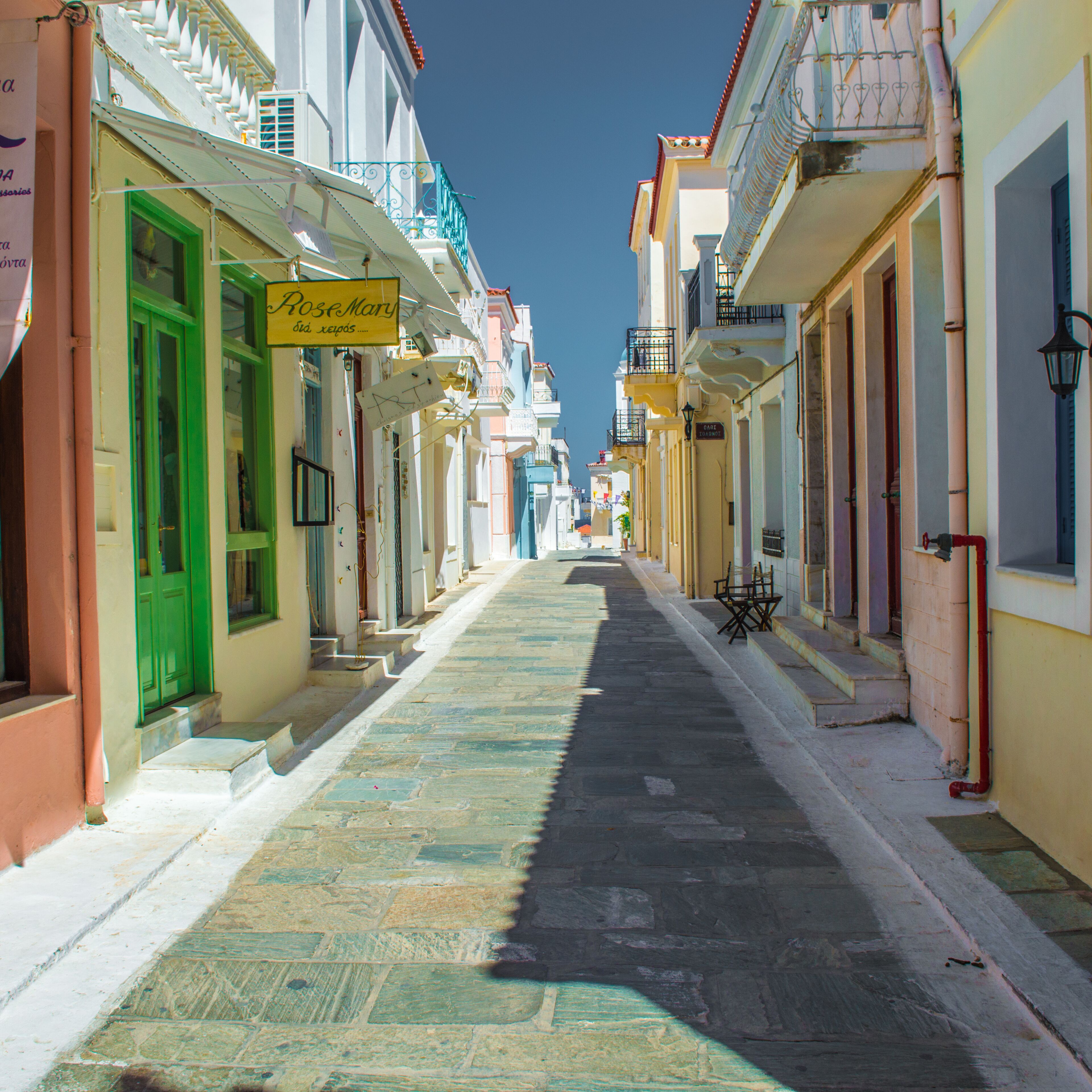 Una calle estrecha bordeada de edificios coloridos, una puerta verde y un letrero que dice 'Rose Mary'.