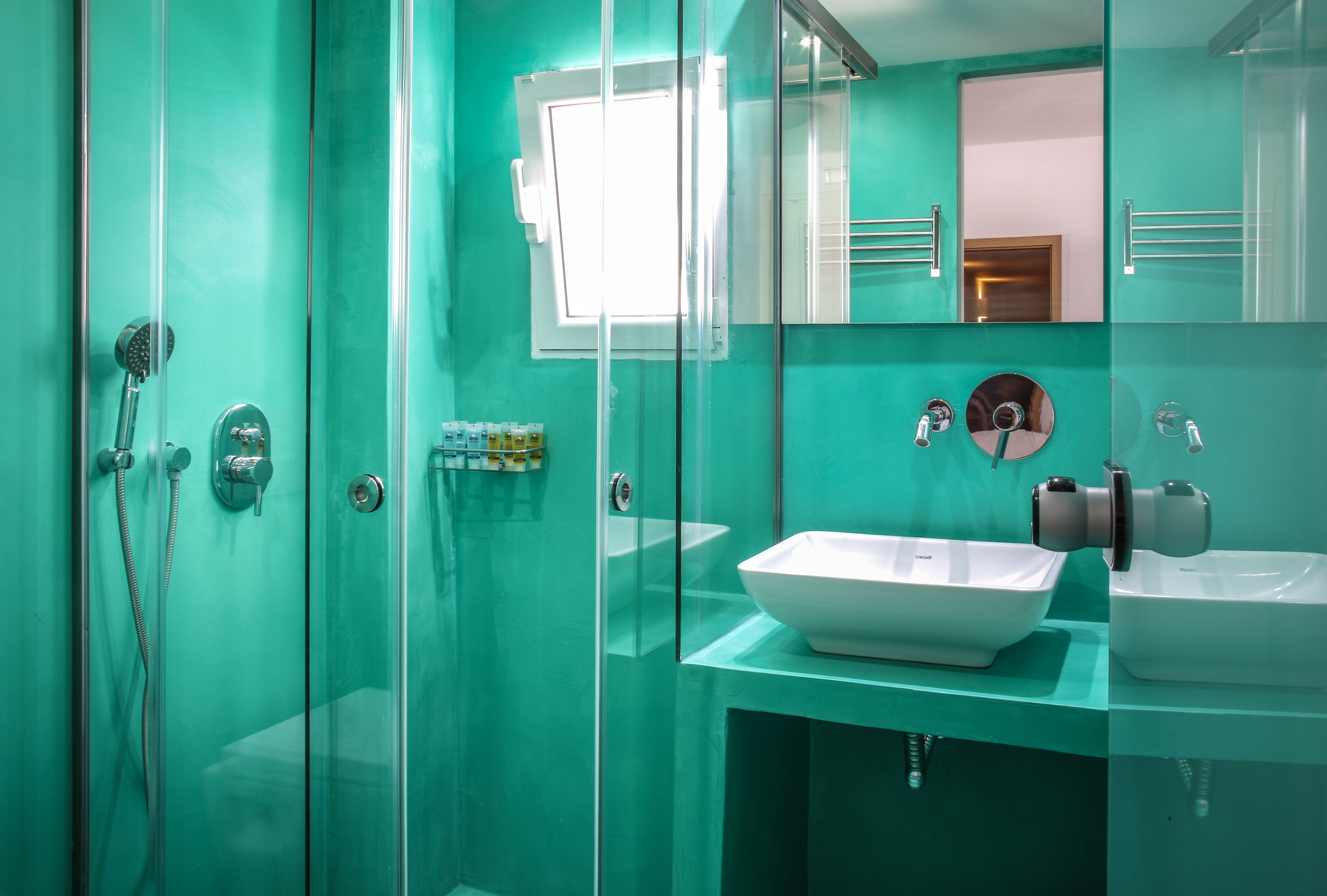 A modern bathroom with a glass shower enclosure, a white sink, and a mirror.