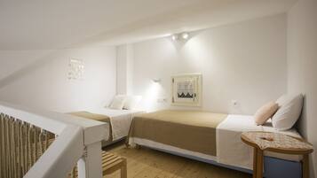 A small, well-lit room with two beds, a wooden floor, and a small table with a lace tablecloth.