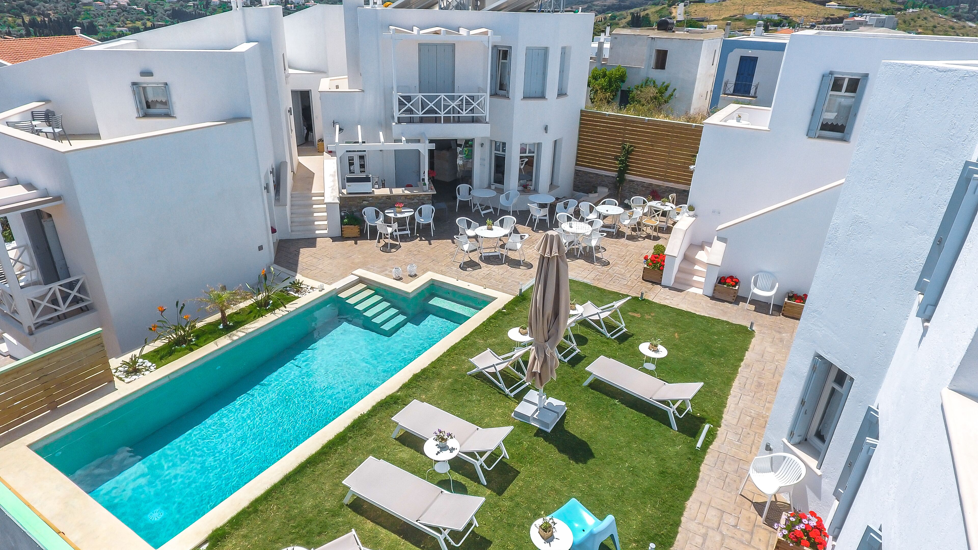 A modern building with a swimming pool, outdoor seating, and a well-maintained garden.