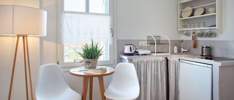 Una cocina compacta con comedor, que incluye una mesa con sillas, una lámpara, una planta en maceta y un refrigerador.