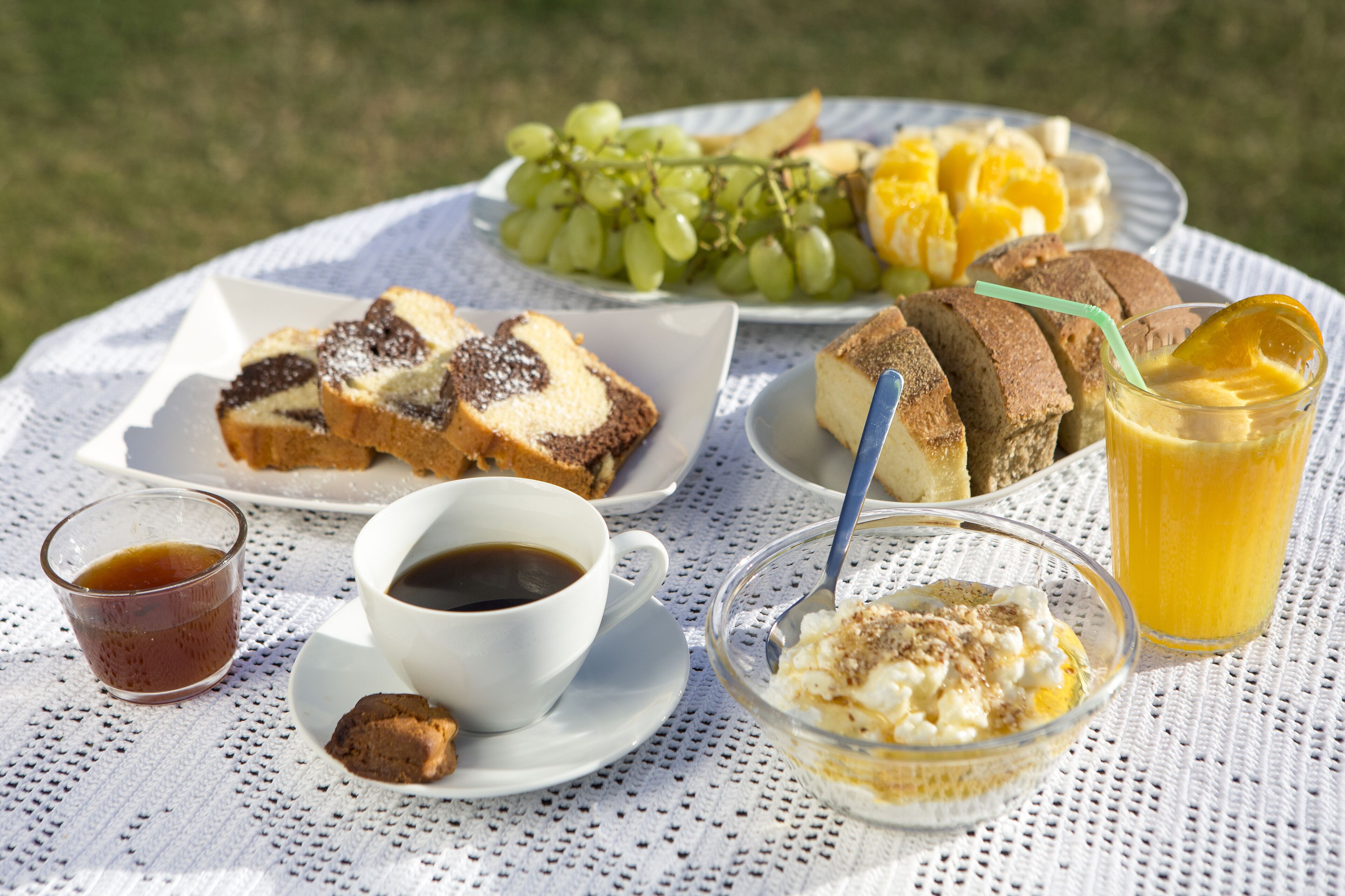A table set with breakfast items including bread, fruit, and beverages.