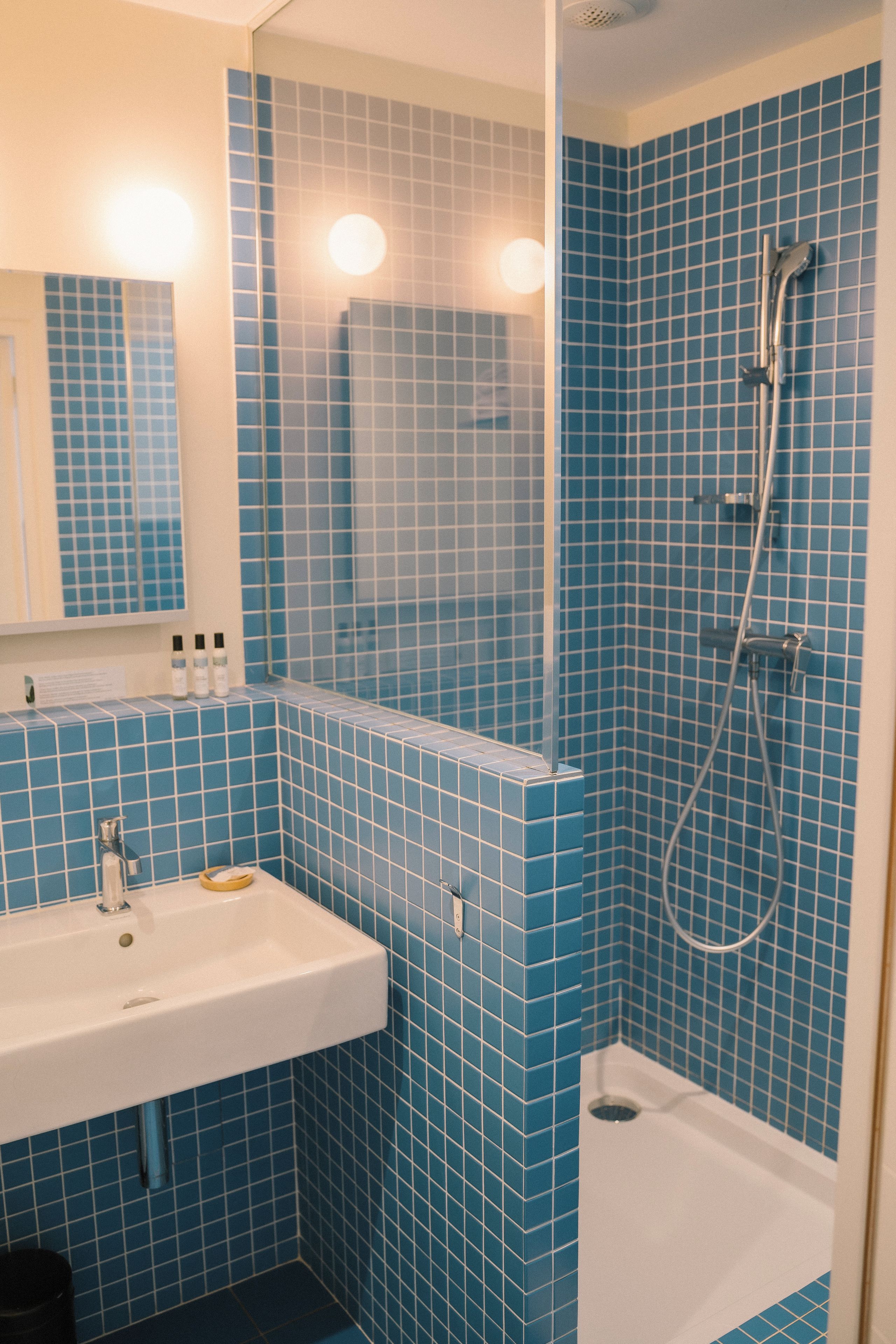 A bathroom with blue tiles, a white sink, and a shower.