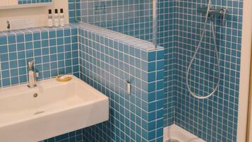 A bathroom with blue tiles, a white sink, and a shower.