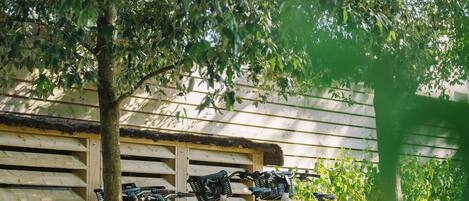 Bicycles parked under a tree in front of a wooden building.