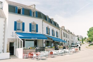 A restaurant with outdoor seating, a blue awning, and a sign reading "Bistro du Bee."