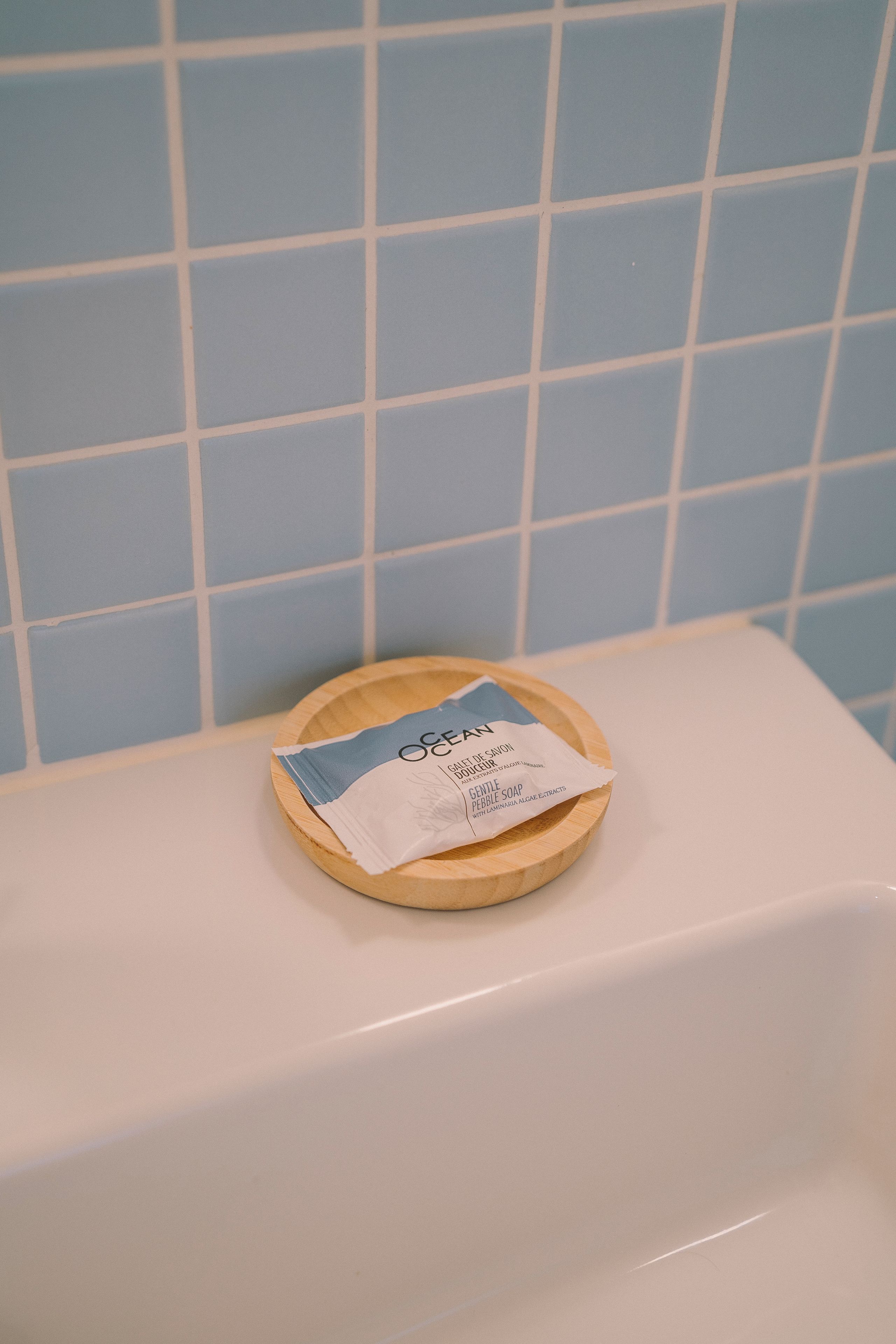 A bathroom with a white bathtub and a wooden tray holding a bar of soap.