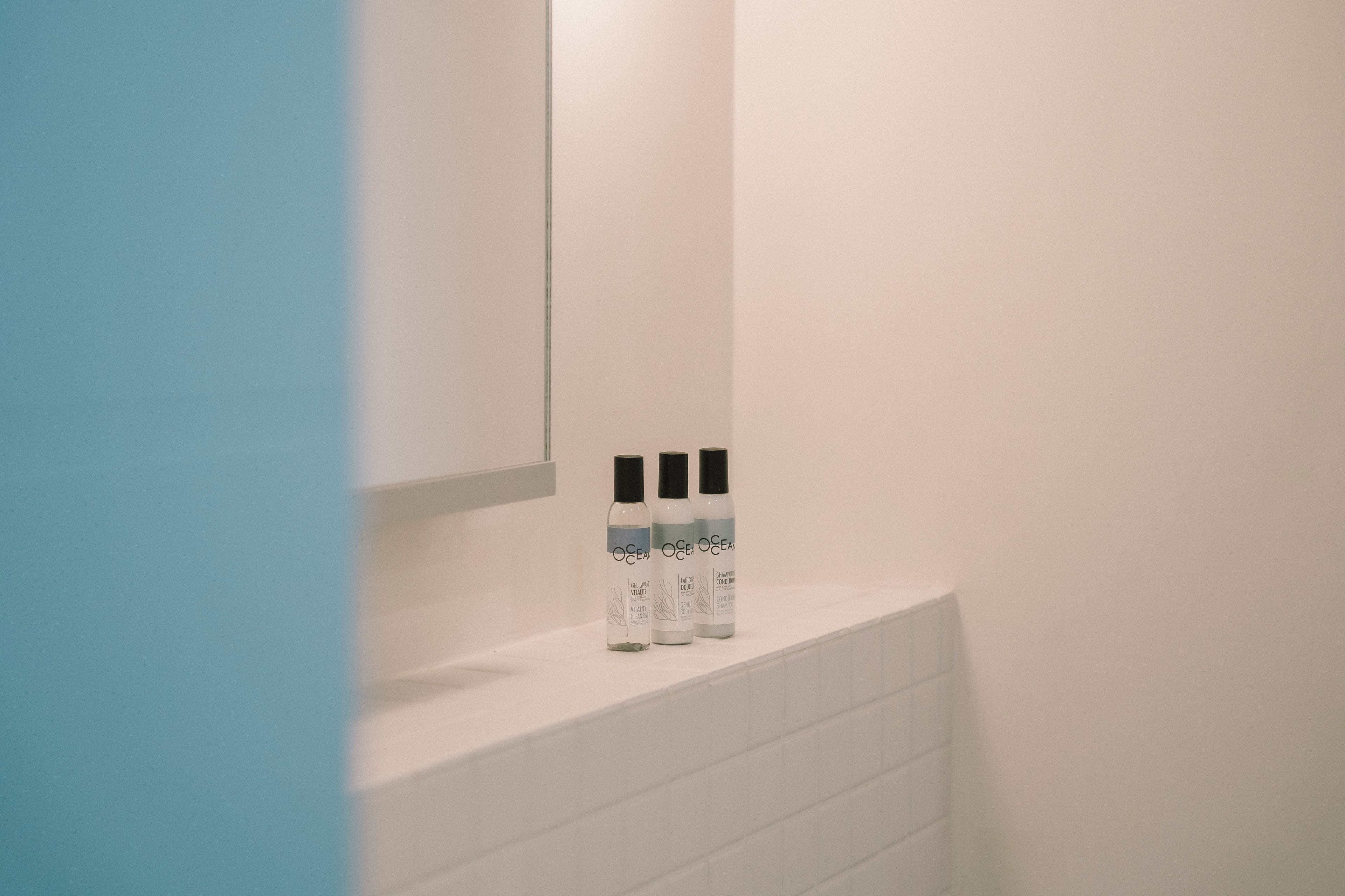 Et badeværelse med en hvid vask og tre flasker Ocean Ocean gel og balsam på bordet.