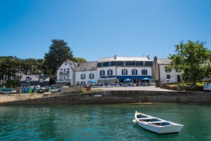 A waterfront building with a dock, a small boat, and a clear blue sky.