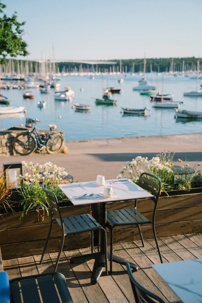 Eine Holzdar Terrasse mit Tisch und Stühlen mit Blick auf eine Marina und Boote.