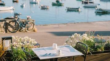 Eine Holzdar Terrasse mit Tisch und Stühlen mit Blick auf eine Marina und Boote.
