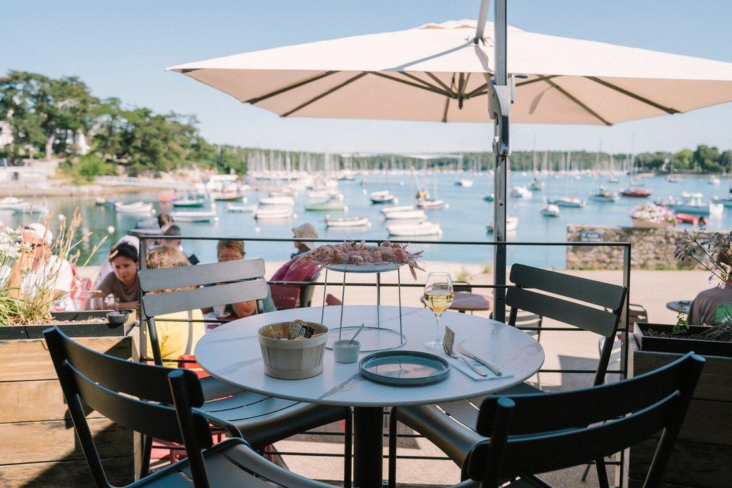 Un área de comedor al aire libre con una mesa, sillas y vistas a barcos en el agua.